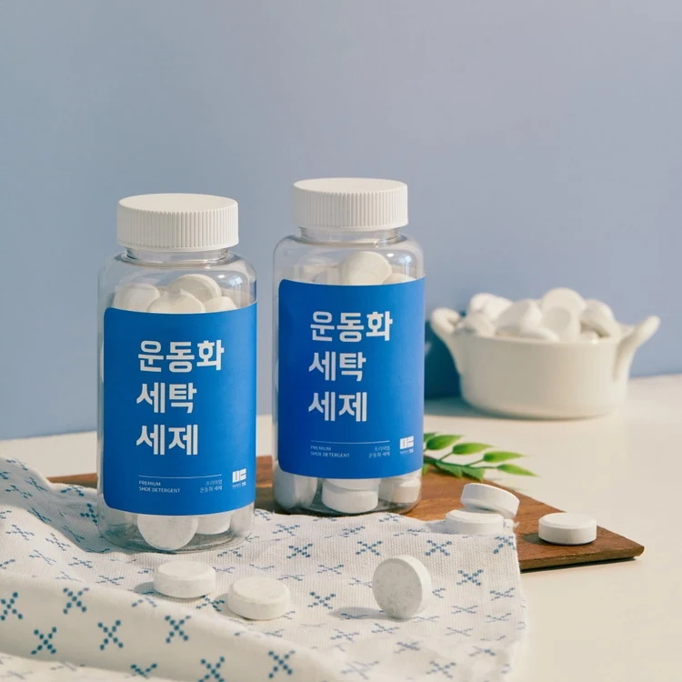 만듬 운동화 세탁 캡슐형 세제 두 통과 흰 정제가 놓인 제품 컷
