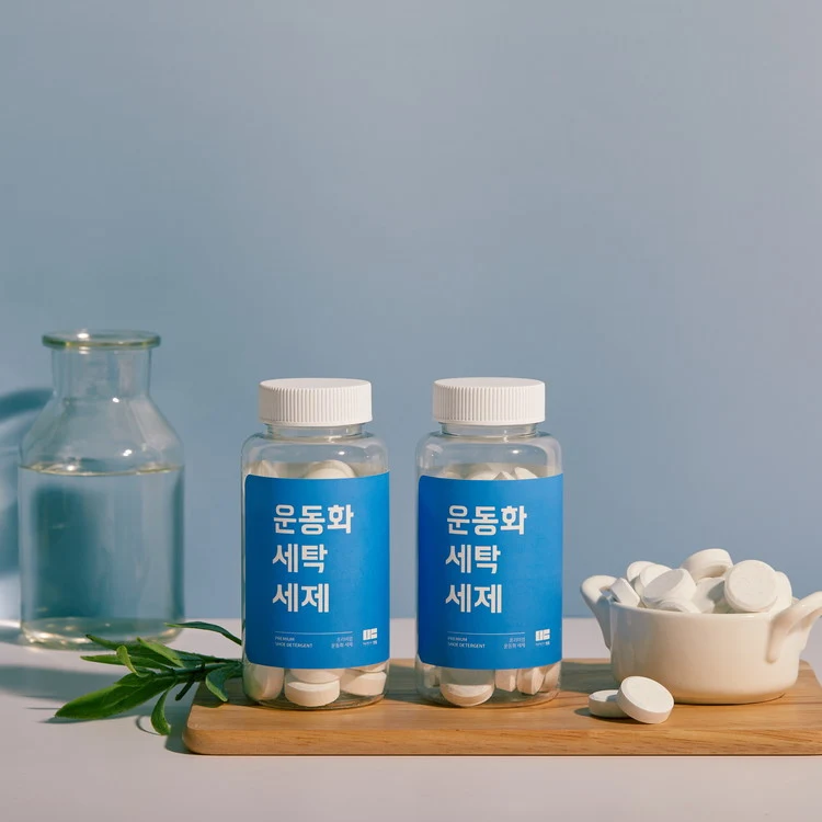 도마 위 만듬 운동화 세탁 세제 한 통과 그릇에 담긴 흰 정제 캡슐